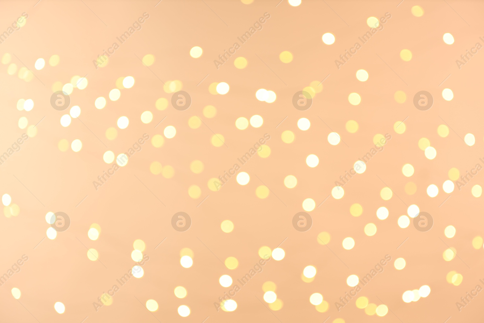 Photo of Blurred view of golden lights on light background, bokeh effect