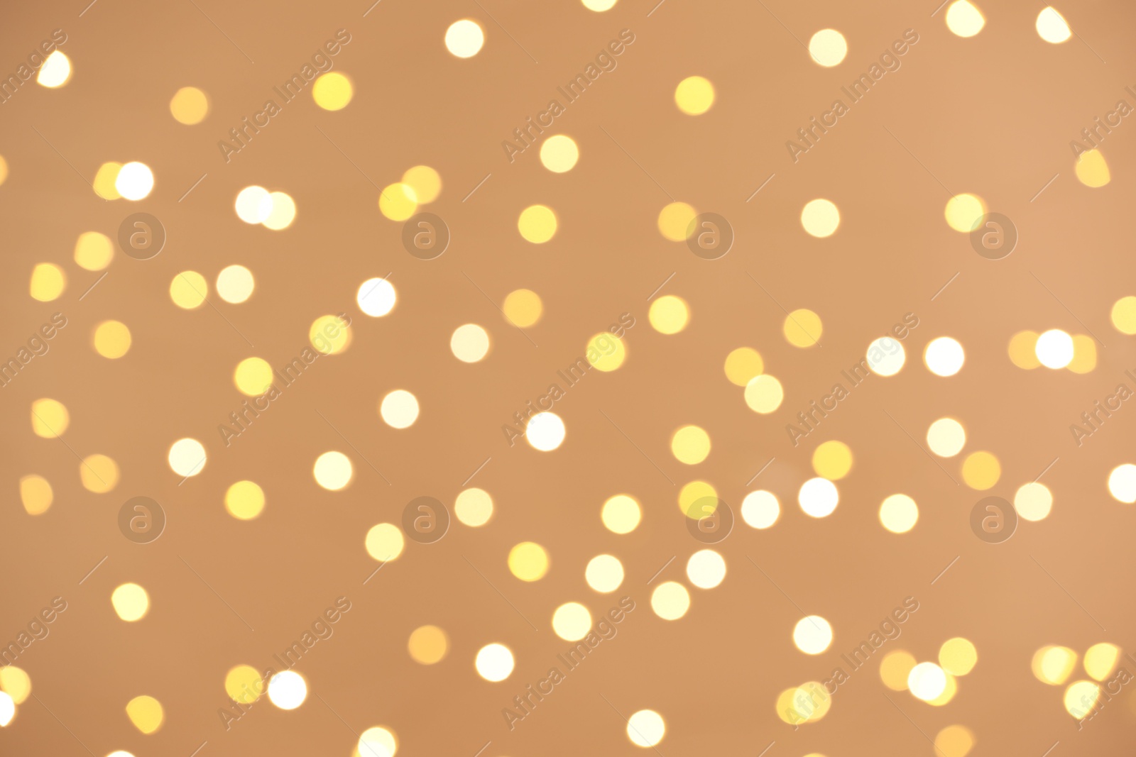 Photo of Blurred view of golden lights on light background, bokeh effect