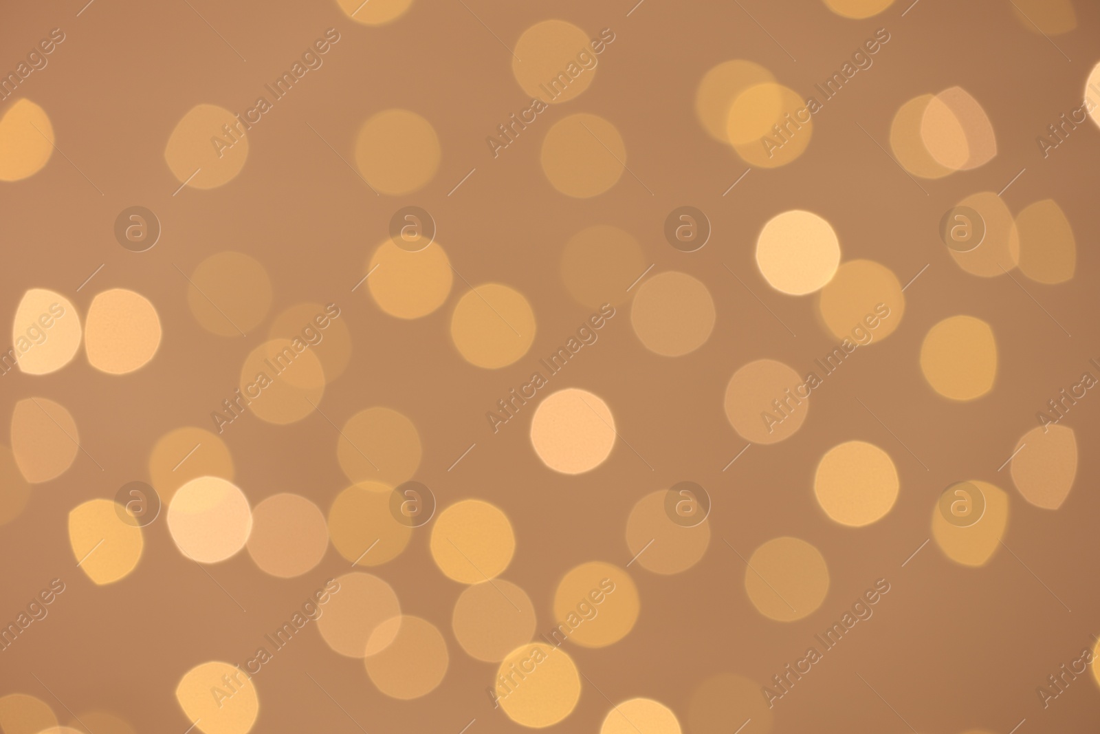 Photo of Blurred view of golden lights on light background, bokeh effect