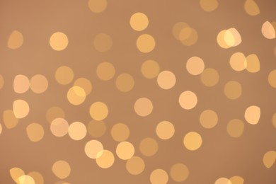 Photo of Blurred view of golden lights on light background, bokeh effect