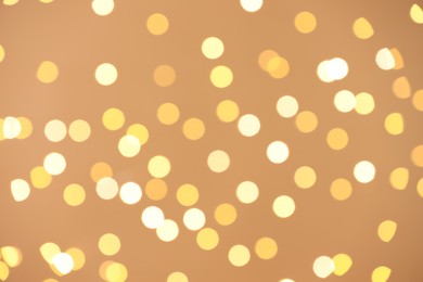 Photo of Blurred view of golden lights on light background, bokeh effect