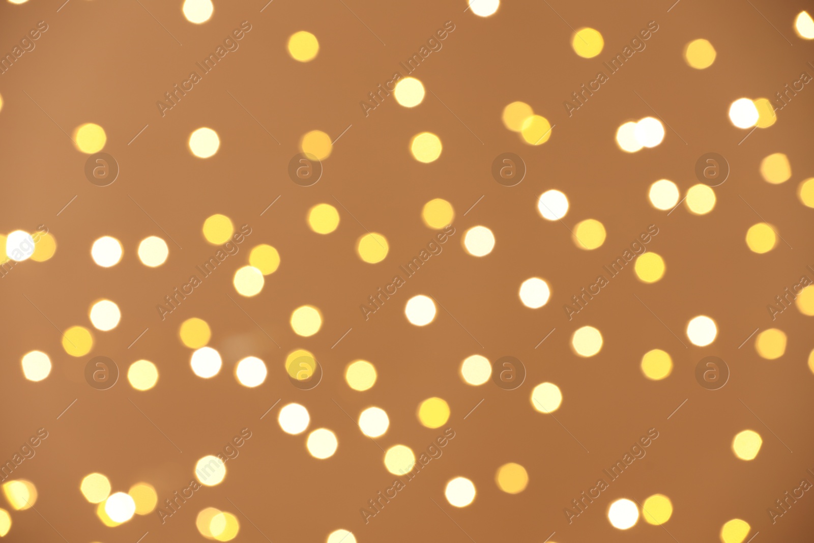 Photo of Blurred view of golden lights on light background, bokeh effect