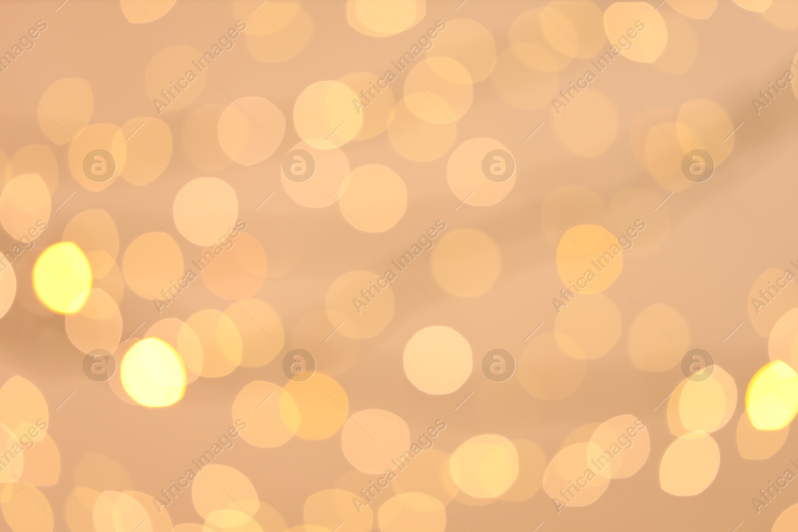 Photo of Blurred view of golden lights on light background, bokeh effect