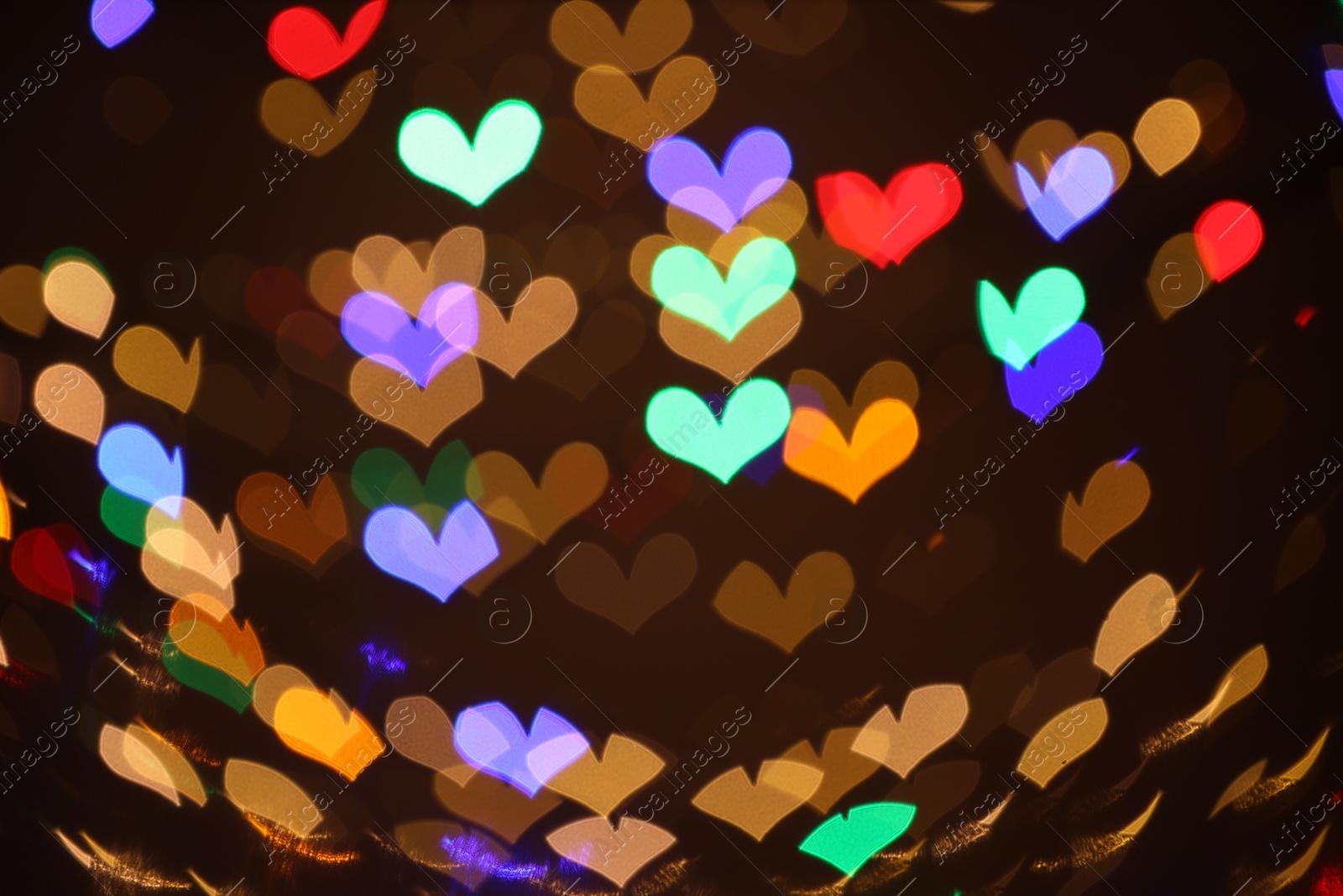 Photo of Blurred view of heart shaped lights on dark background, bokeh effect