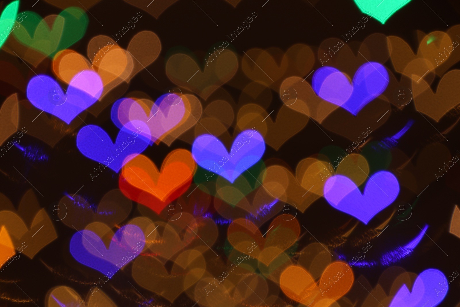 Photo of Blurred view of heart shaped lights on dark background, bokeh effect