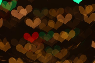 Photo of Blurred view of heart shaped lights on dark background, bokeh effect