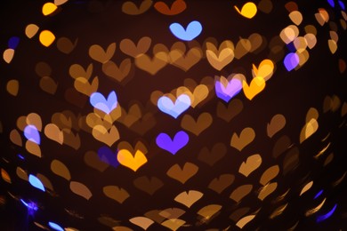 Photo of Blurred view of heart shaped lights on dark background, bokeh effect