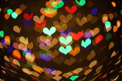 Photo of Blurred view of heart shaped lights on dark background, bokeh effect