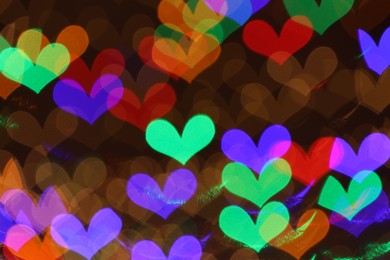 Photo of Blurred view of heart shaped lights on dark background, bokeh effect