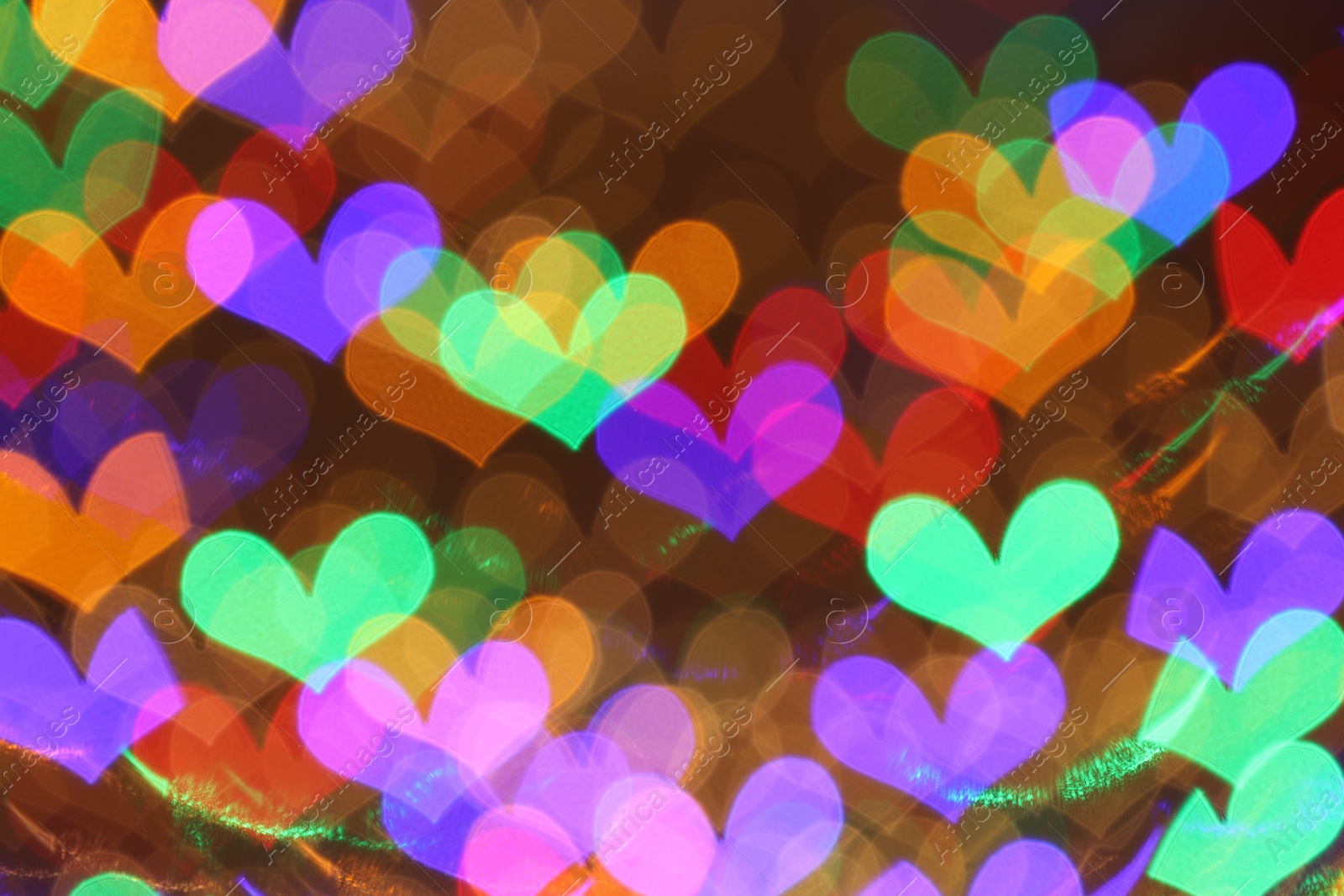 Photo of Blurred view of heart shaped lights on color background, bokeh effect