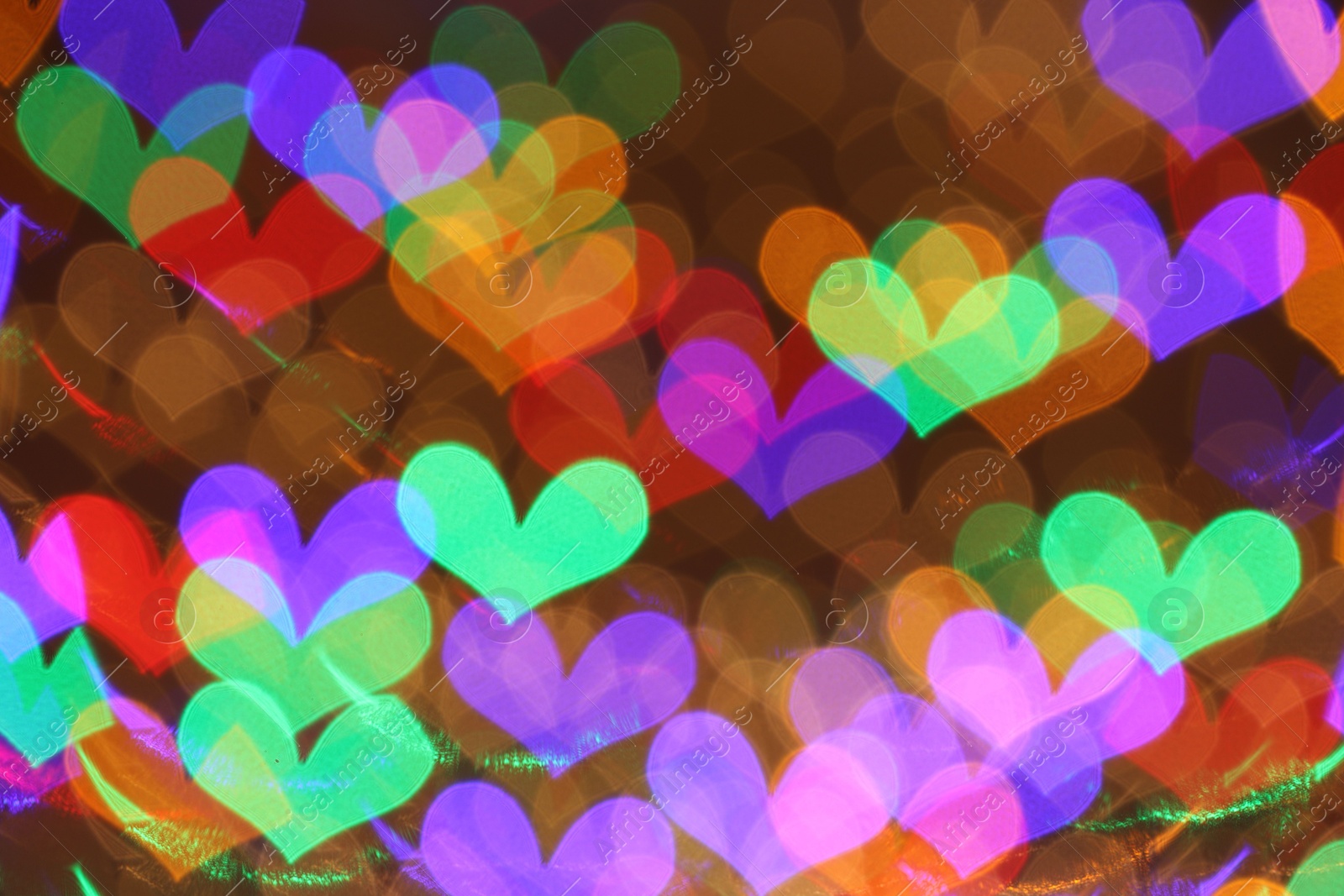 Photo of Blurred view of heart shaped lights on color background, bokeh effect