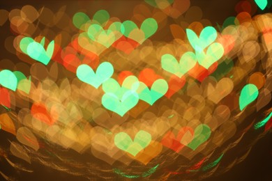 Photo of Blurred view of heart shaped lights on color background, bokeh effect