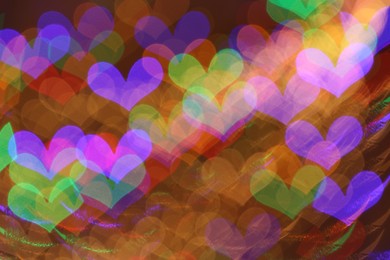 Photo of Blurred view of heart shaped lights on color background, bokeh effect