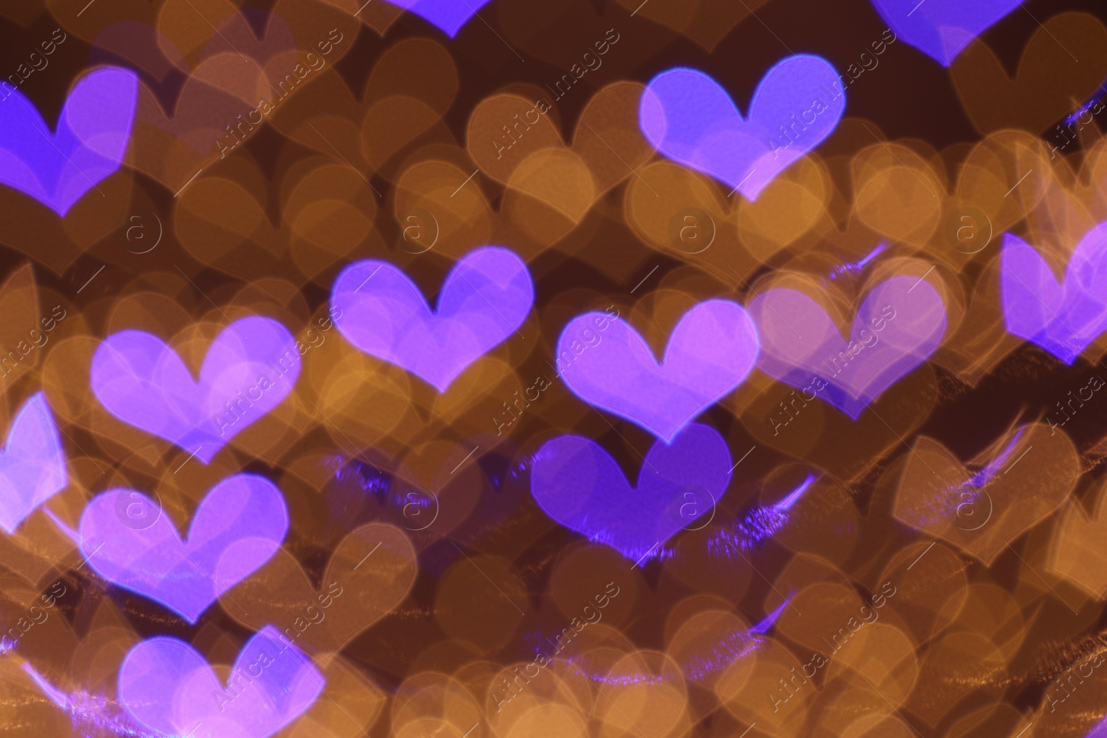 Photo of Blurred view of heart shaped lights on color background, bokeh effect