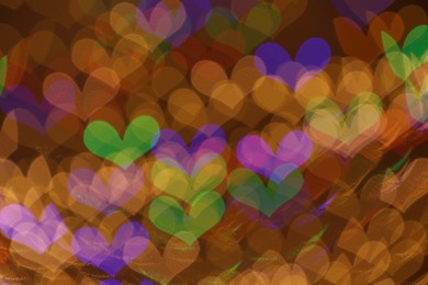 Photo of Blurred view of heart shaped lights on color background, bokeh effect