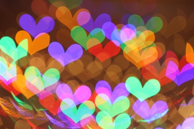 Photo of Blurred view of heart shaped lights on color background, bokeh effect