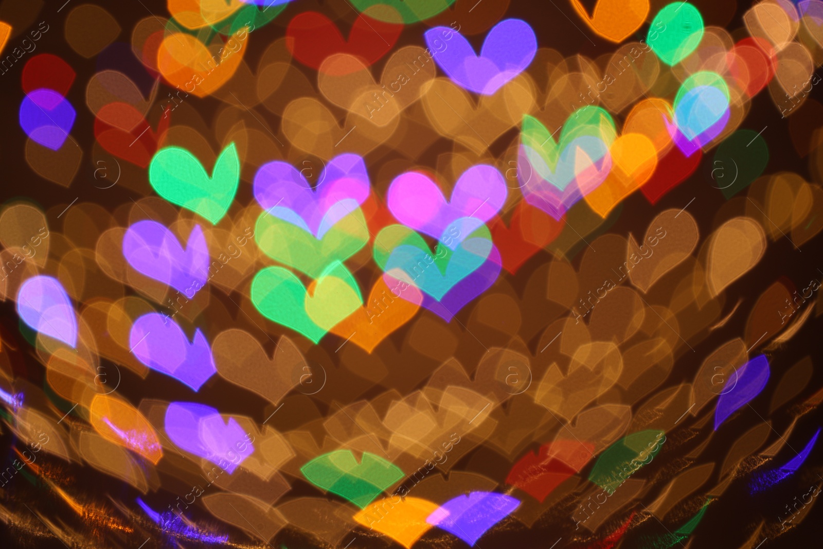 Photo of Blurred view of heart shaped lights on color background, bokeh effect