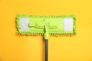 Microfiber mop on yellow background, top view. Cleaning equipment