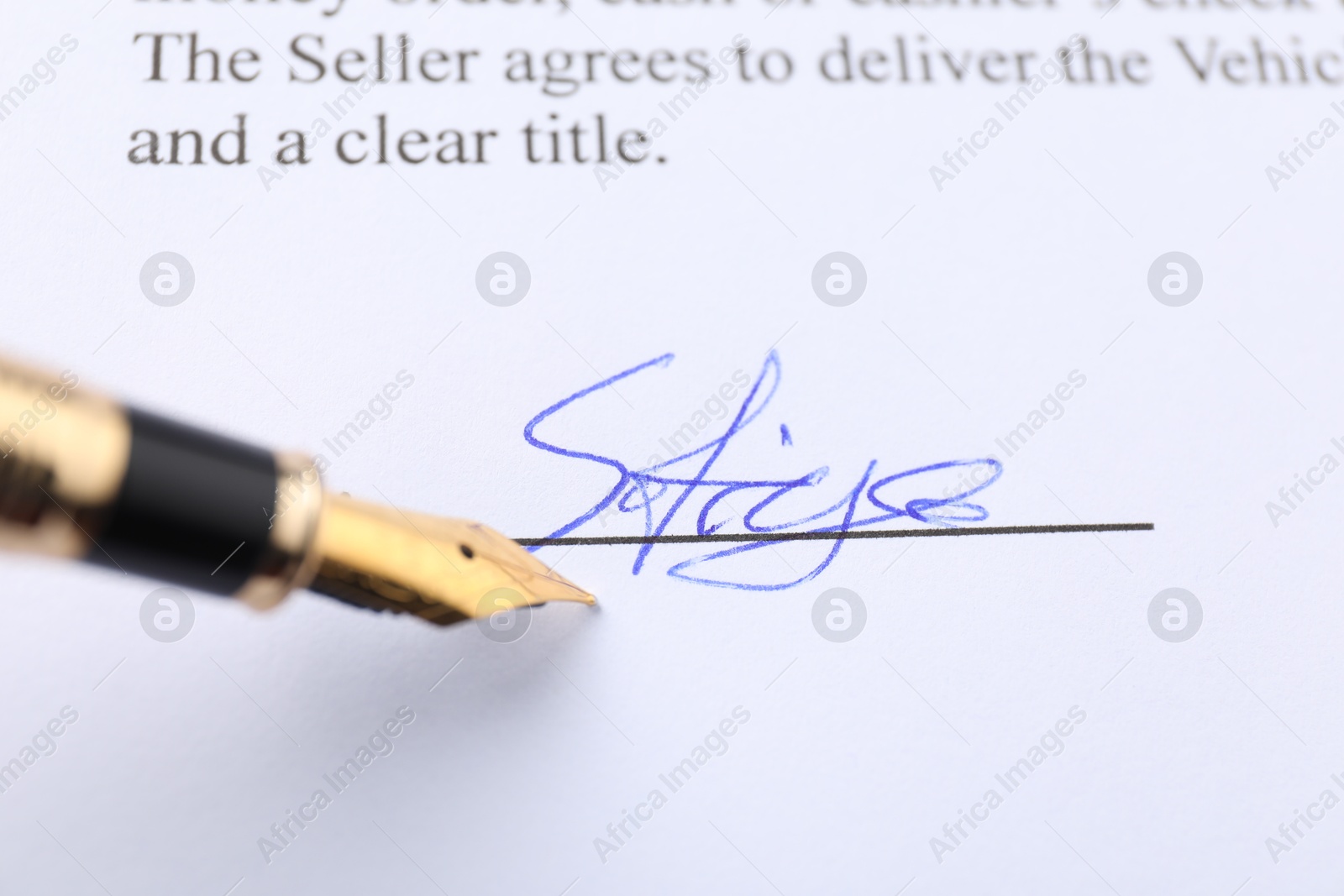 Photo of Signature and fountain pen on paperwork, closeup view