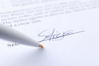 Photo of Signature and pen on paperwork, closeup view