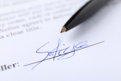 Photo of Signature and pen on paperwork, closeup view