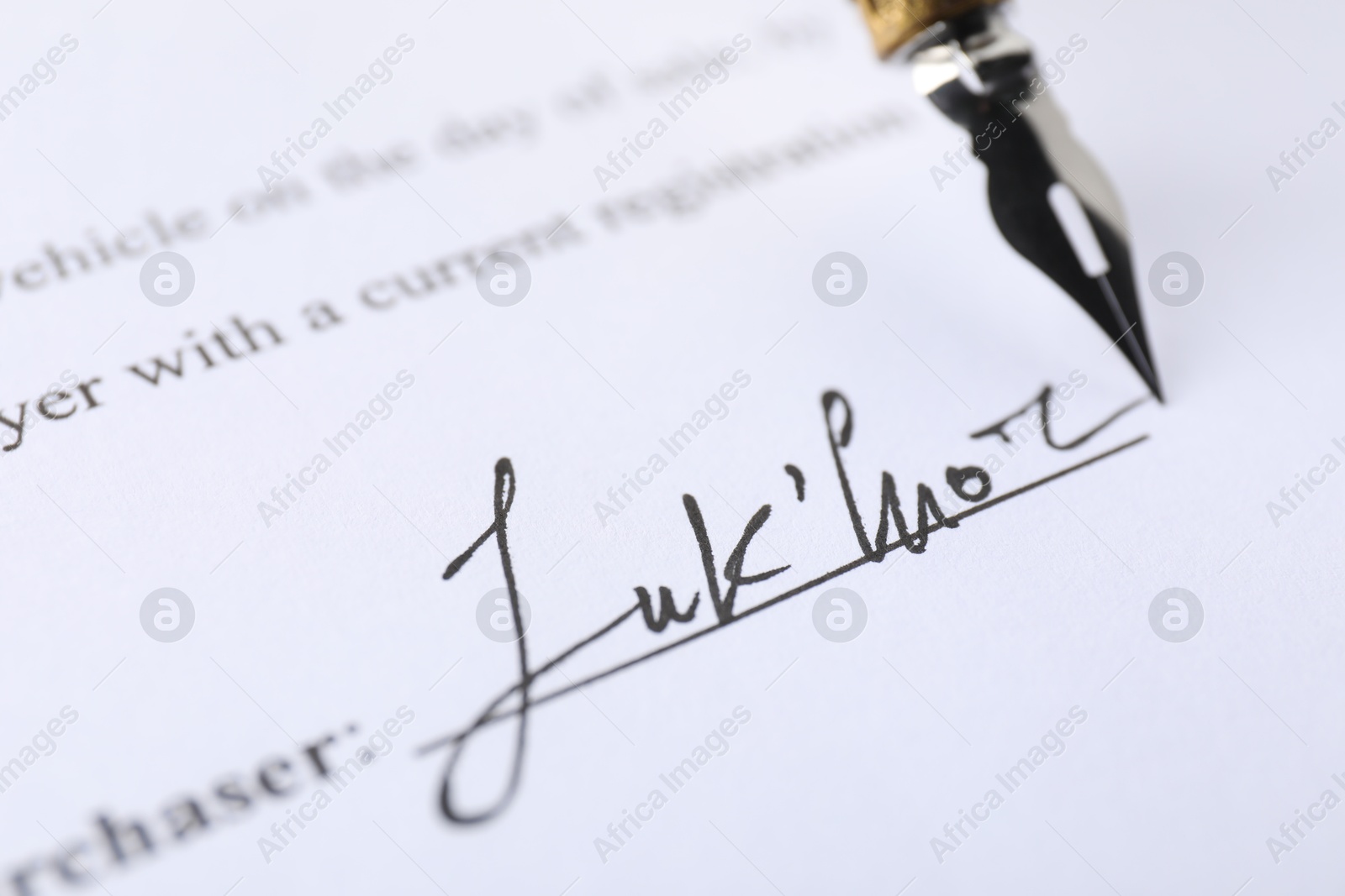 Photo of Signature and fountain pen on paperwork, closeup view