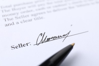 Photo of Signature and pen on paperwork, closeup view