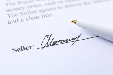 Photo of Signature and pen on paperwork, closeup view