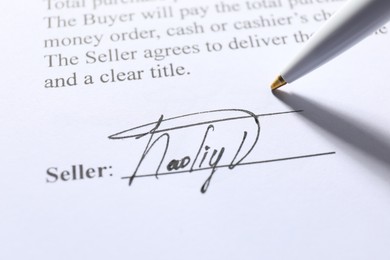 Photo of Signature and pen on paperwork, closeup view