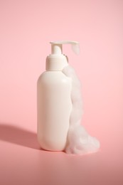 Photo of Bottle of cosmetic product with foam on pink background