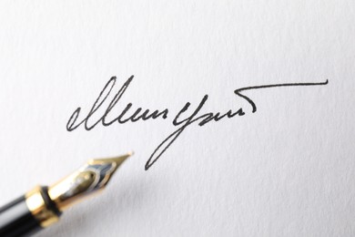 Photo of Fountain pen and signature on white paper, closeup