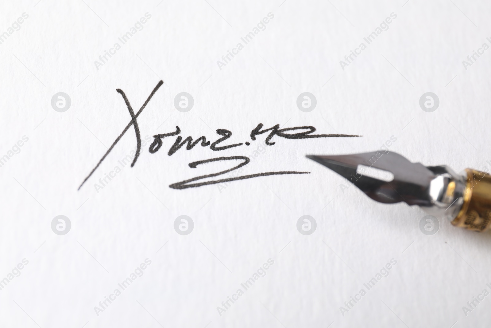 Photo of Fountain pen and signature on white paper, closeup