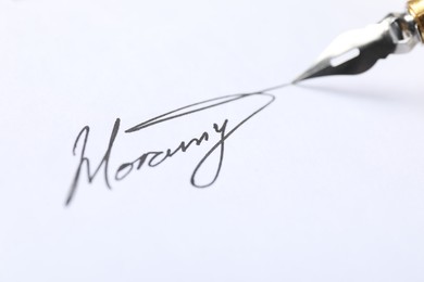 Photo of Fountain pen leaving signature on paper, closeup