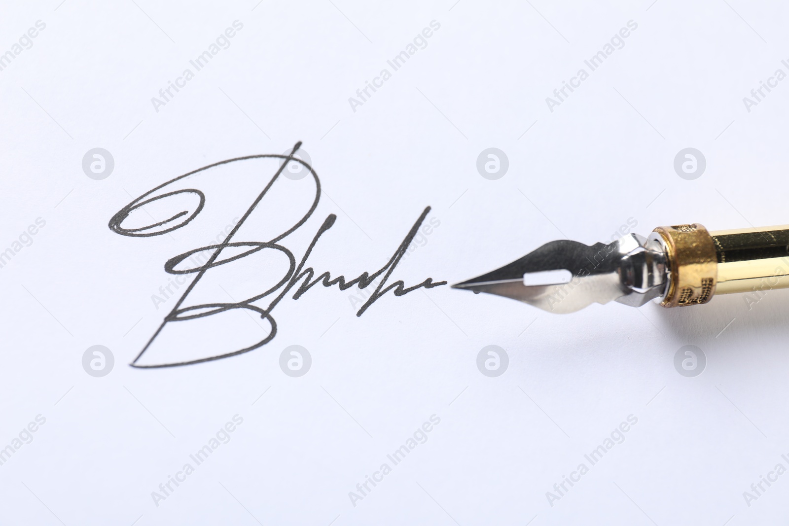 Photo of Fountain pen and signature on white paper, closeup