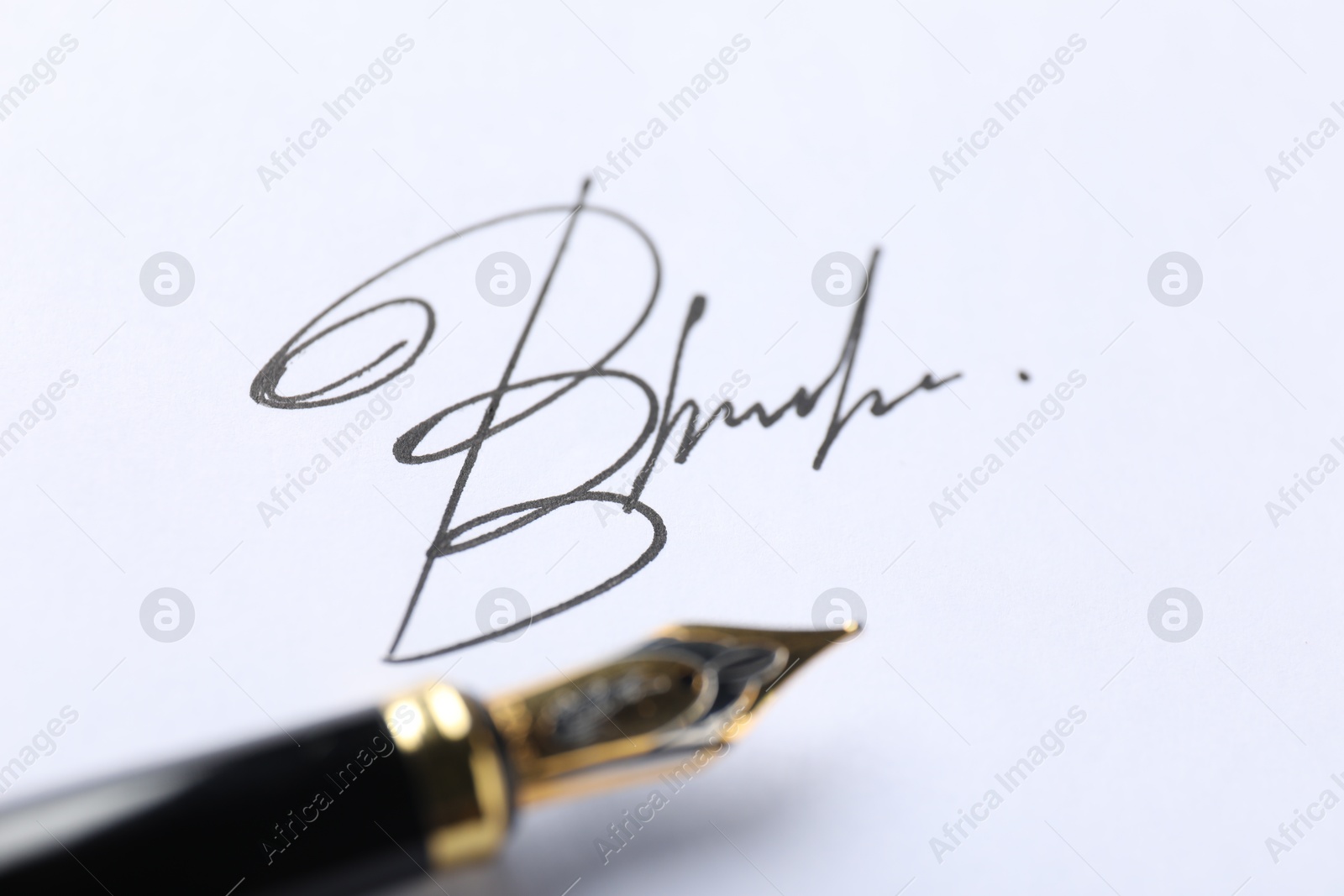 Photo of Fountain pen and signature on white paper, closeup