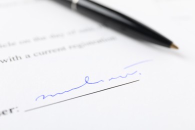 Photo of Signature and pen on paperwork, closeup view