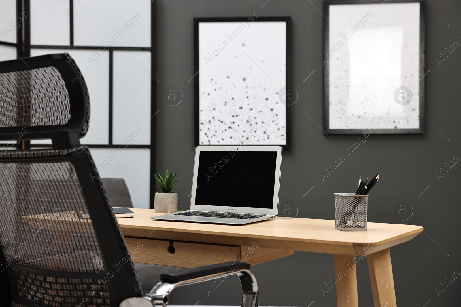 Photo of Comfortable workplace with modern laptop on wooden table indoors