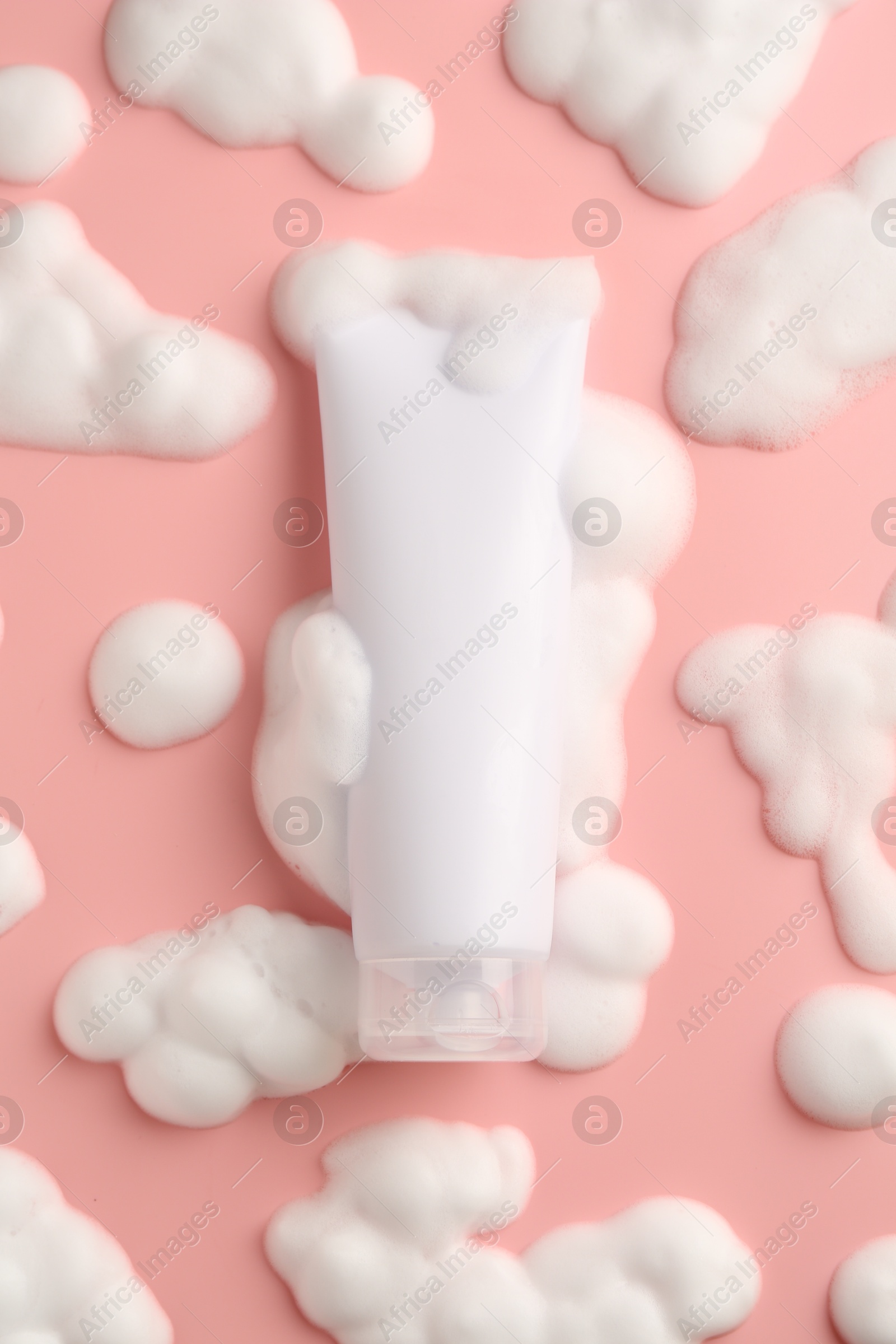 Photo of Tube of cosmetic product with foam on pink background, top view