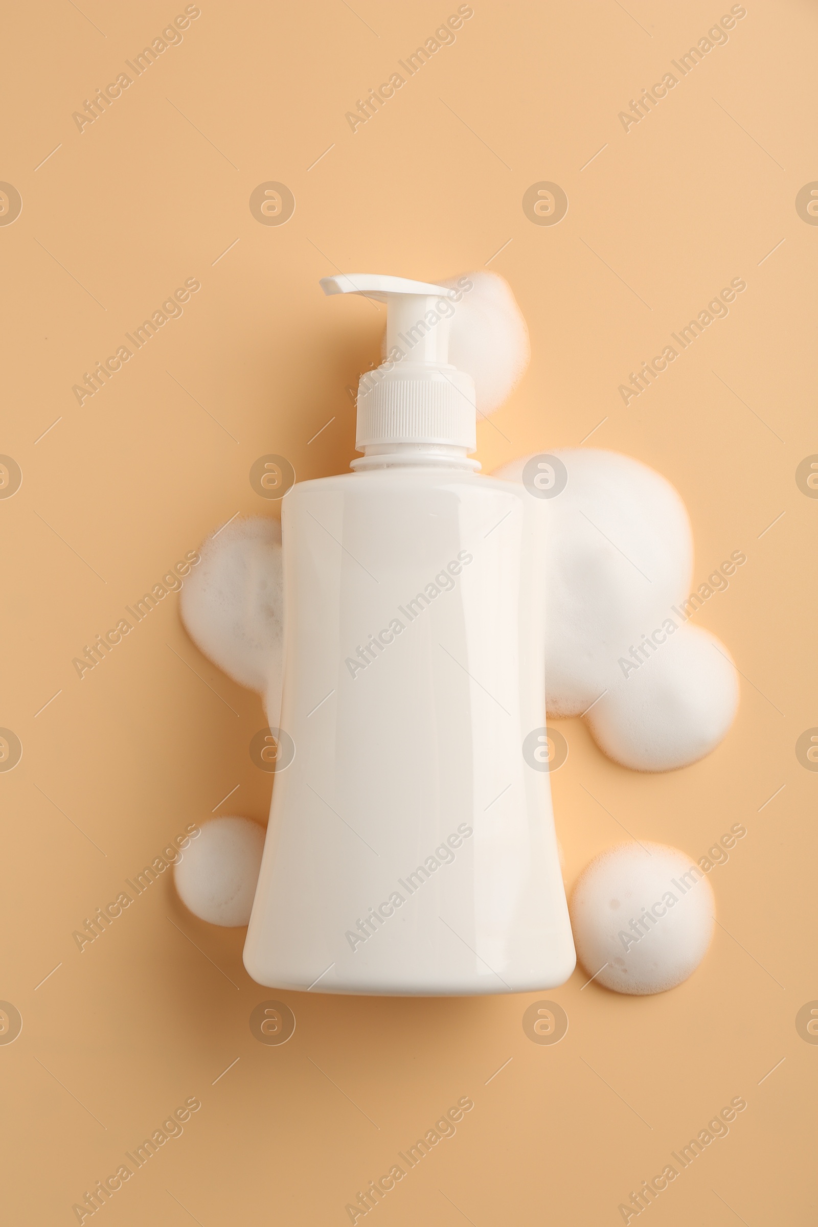 Photo of Bottle of cosmetic product with foam on beige background, top view