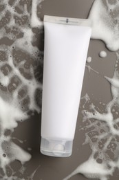 Photo of Tube of cosmetic product with foam on grey background, top view