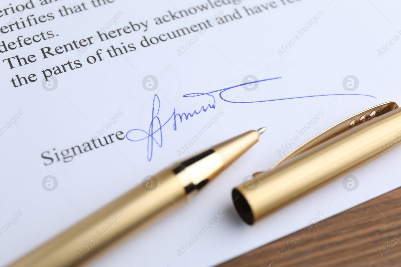 Photo of Ballpoint pen and signature on contract at wooden table, closeup