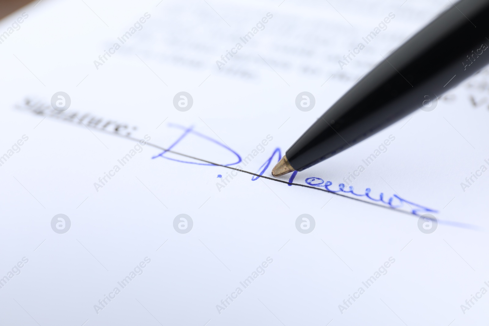 Photo of Ballpoint pen leaving signature on contract, closeup