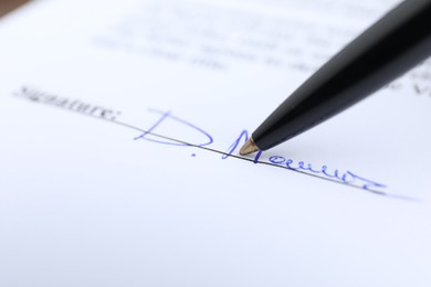 Photo of Ballpoint pen leaving signature on contract, closeup