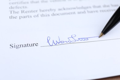 Photo of Ballpoint pen leaving signature on contract, closeup