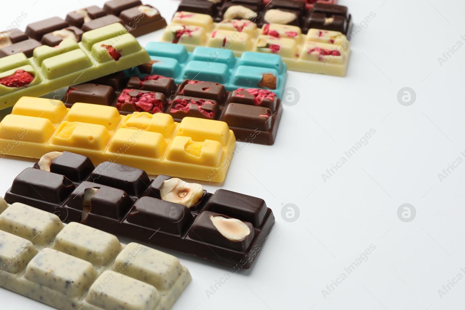 Photo of Different tasty chocolate bars on white background, closeup. Space for text