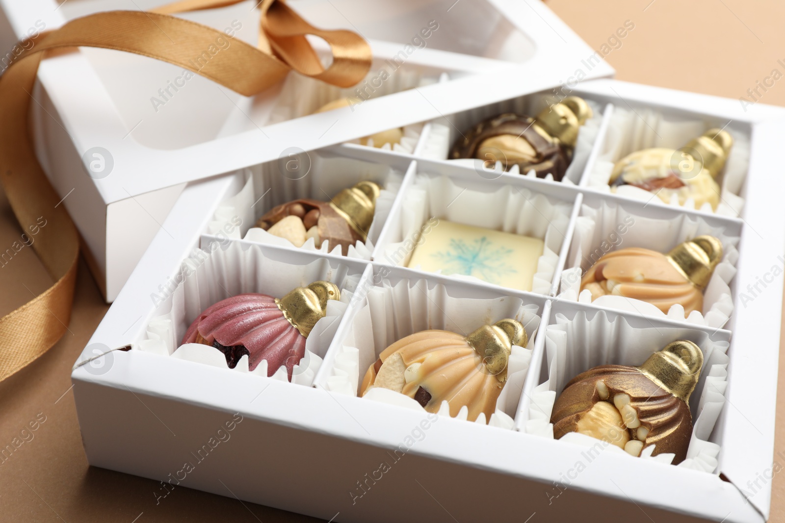 Photo of Delicious chocolate in shape of Christmas ornaments in open box on beige background, closeup