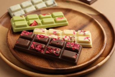 Photo of Different tasty chocolate bars on beige background, closeup