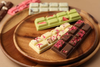 Photo of Different tasty chocolate bars on beige background, closeup