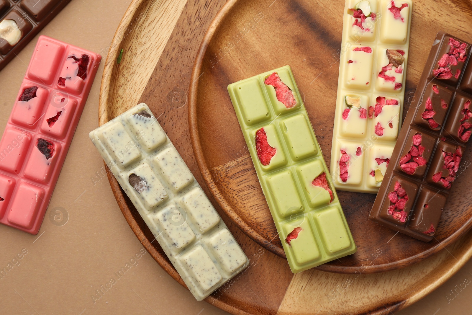 Photo of Different tasty chocolate bars on beige background, flat lay