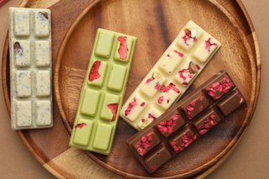 Photo of Different tasty chocolate bars on beige background, top view